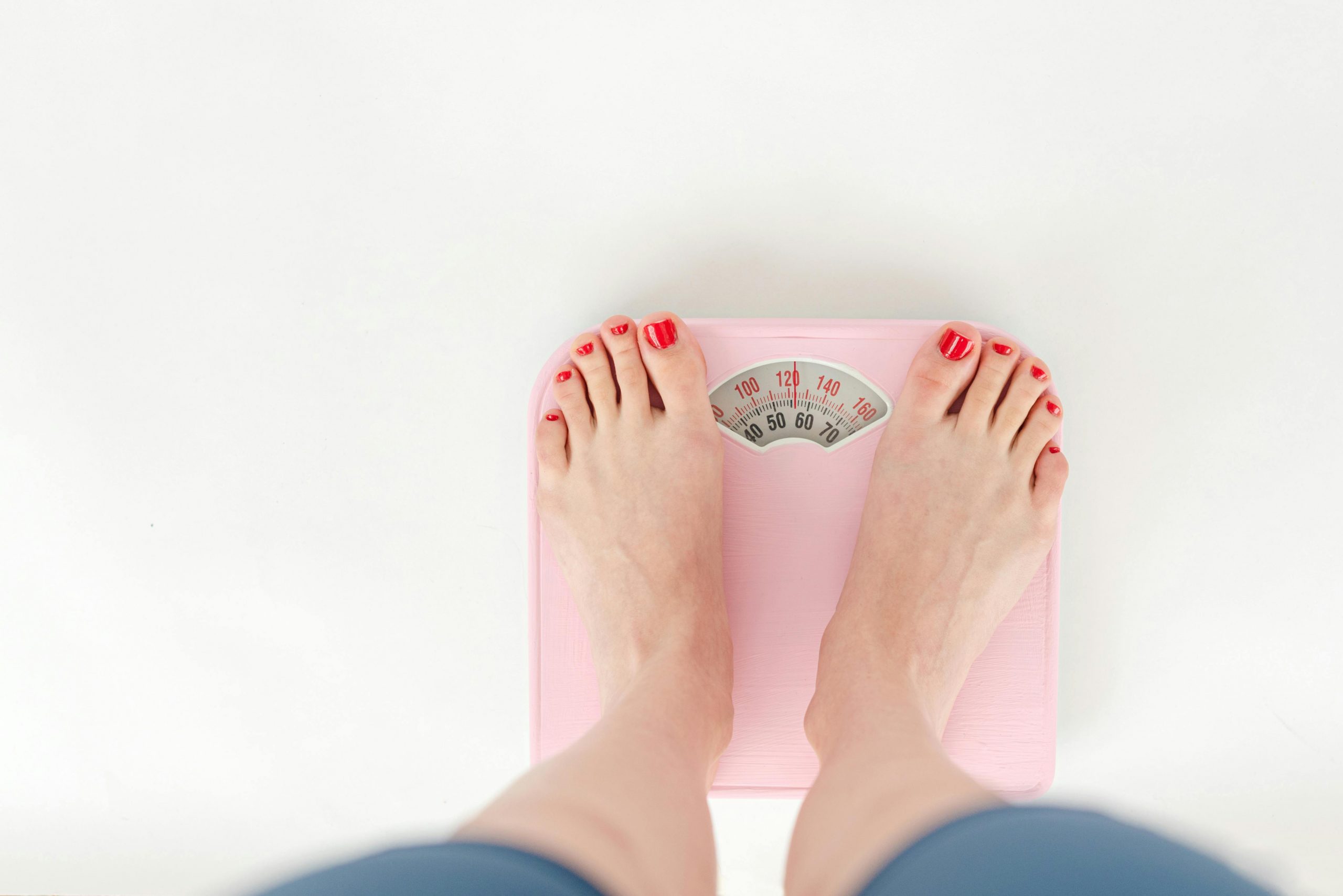 feet with red nail polish standing on a weighing scale